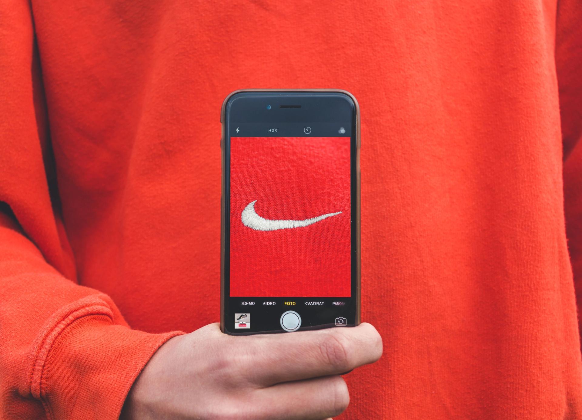 A person is holding a cell phone with a picture of a Nike logo on the screen.