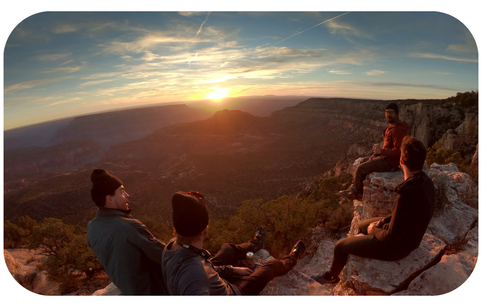 A group of brand ambassadors sitting on top of a mountain at sunset, symbolizing the peak of success in ambassador programs