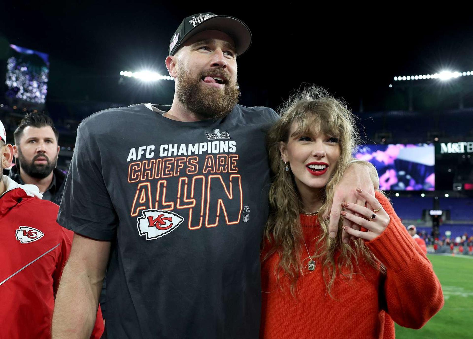 A man and a woman, identified as pop star Taylor Swift and football player Travis Kelce, posing together on a football field, symbolizing their popular relationship in 2024