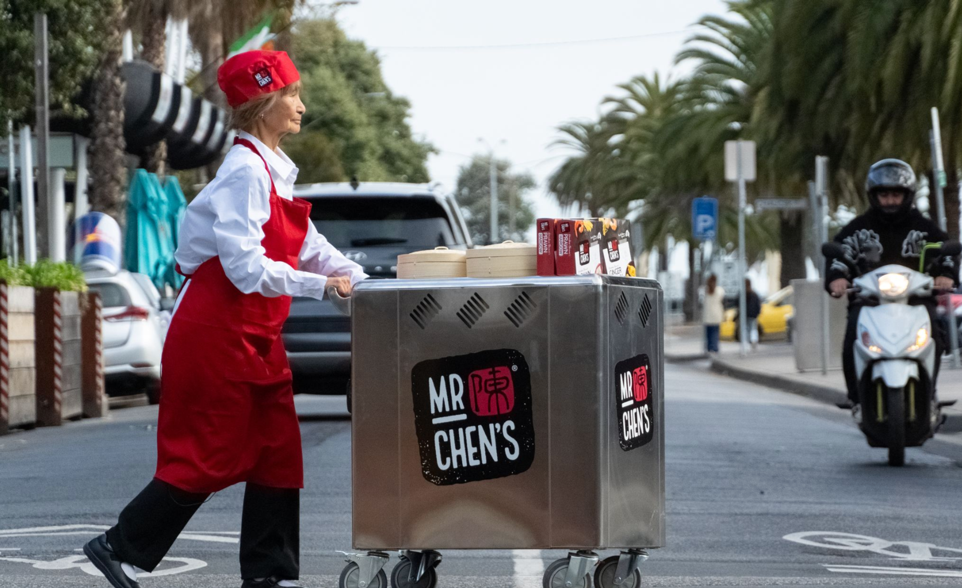 A woman is pushing a cart that says mr chen 's on it