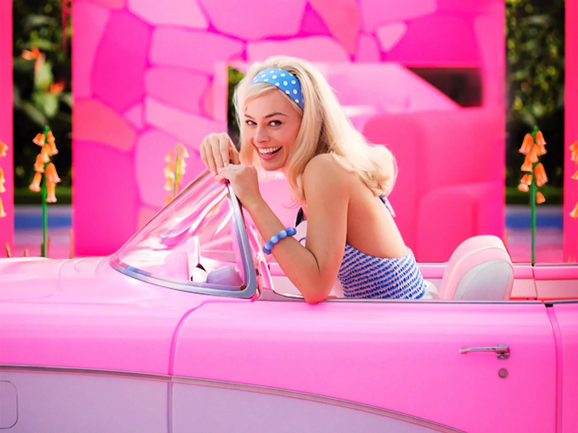 Barbie movie scene with a woman sitting in a pink car