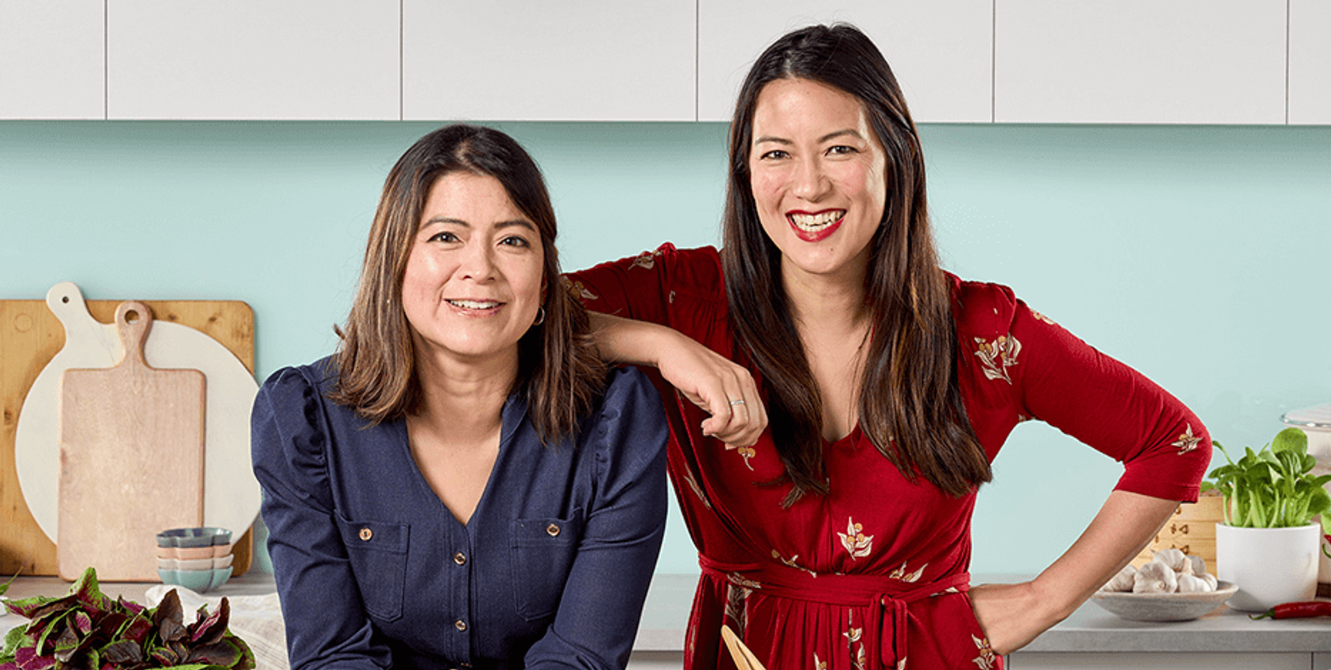 Sisters Lucy and Nancy Chen, owners of the family-owned business Mr. Chen's, standing together in a kitchen, representing the tradition and authenticity of their brand that offers a variety of Asian cuisine including dumplings, gyoza, baos, and buns to Australian households.