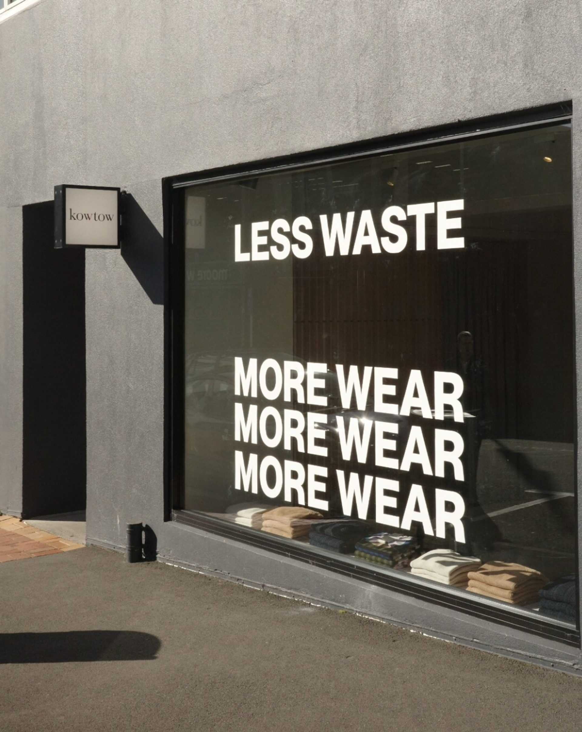 A store front with a sign that says less waste... more wear, more wear, more wear