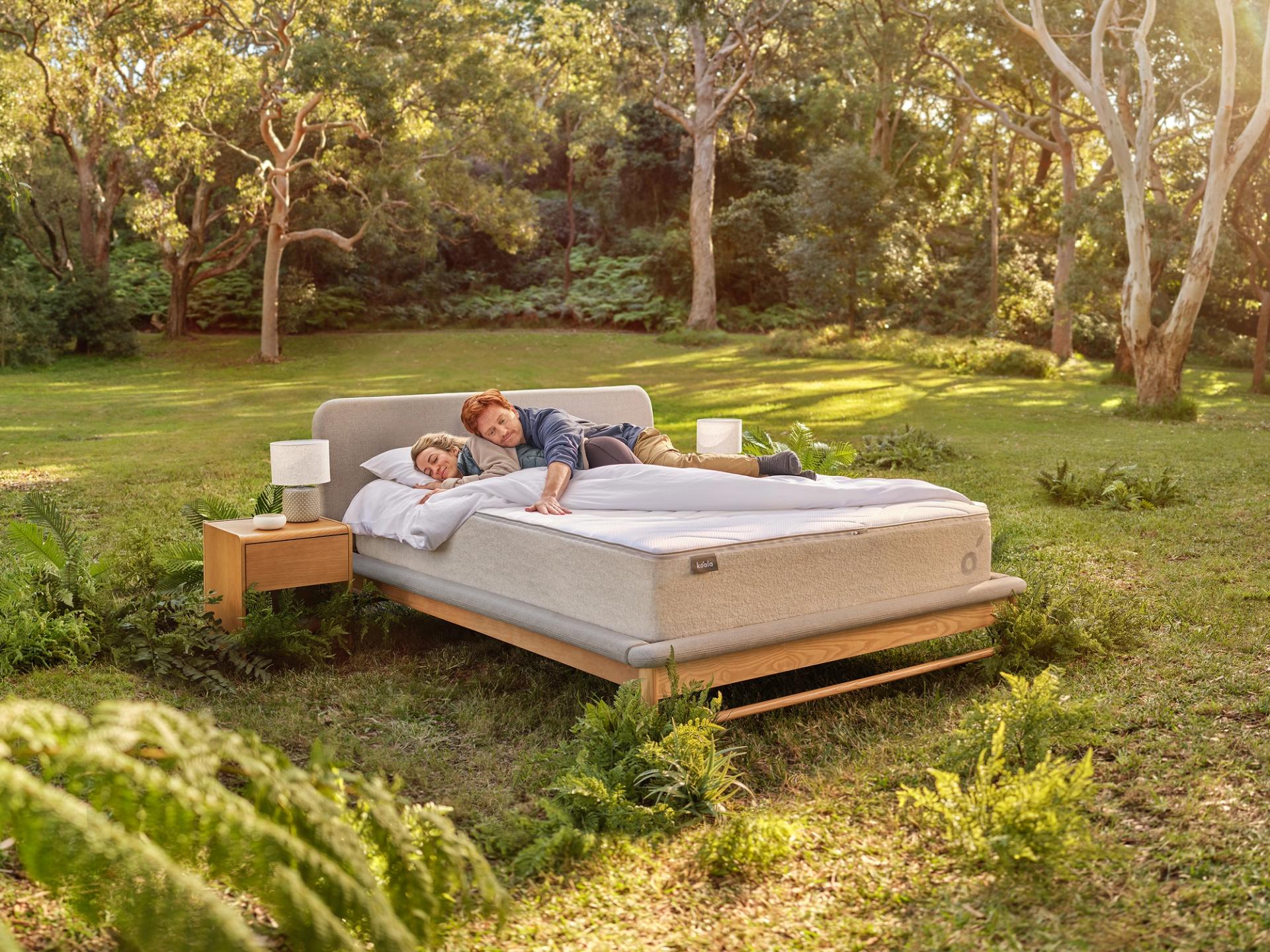A couple of people are laying on a bed in the middle of the outdoors.
