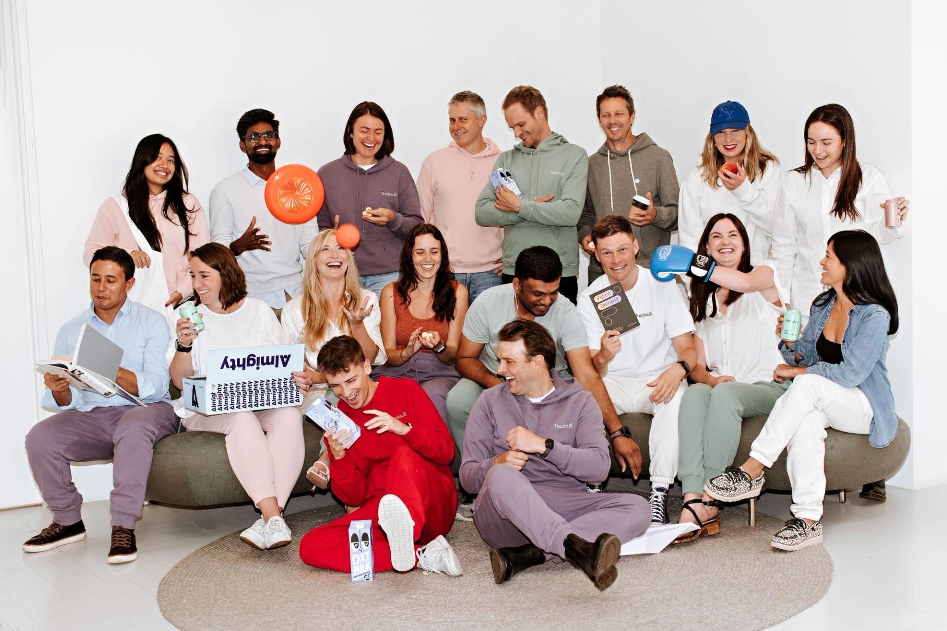 The Tracksuit team posing for a picture while sitting on a couch