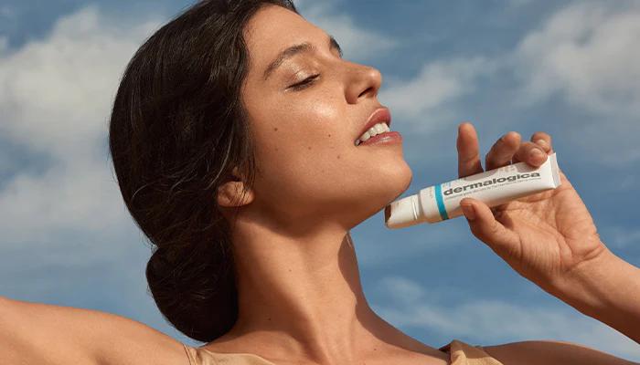 A woman applying Dermalogica lip balm, a premium skincare product, to her lips