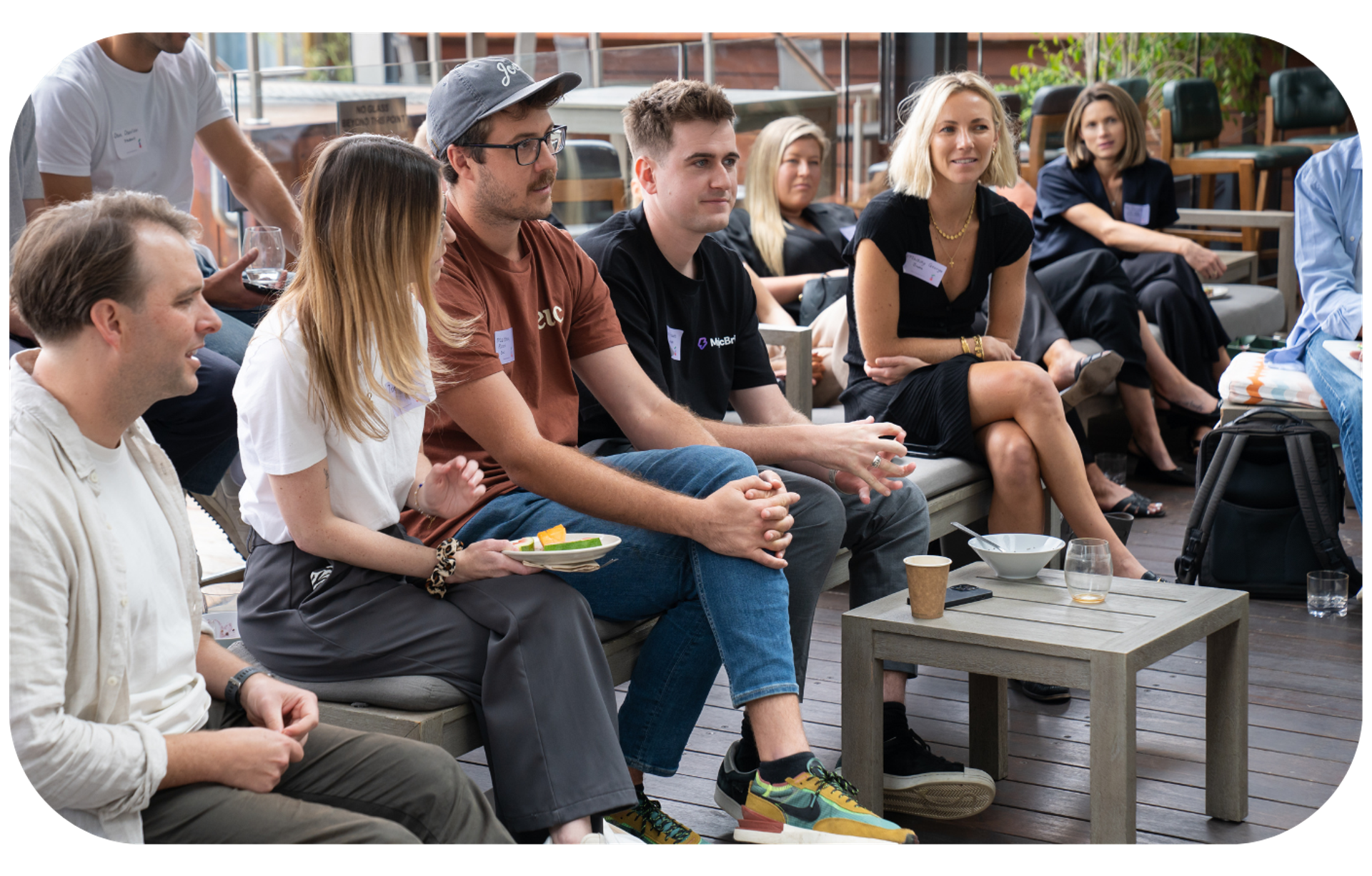 A group of professionals engaged in a discussion at a marketing event, with one man wearing a shirt with the letter 'A' on it, symbolizing the collaborative nature of brand building discussions.