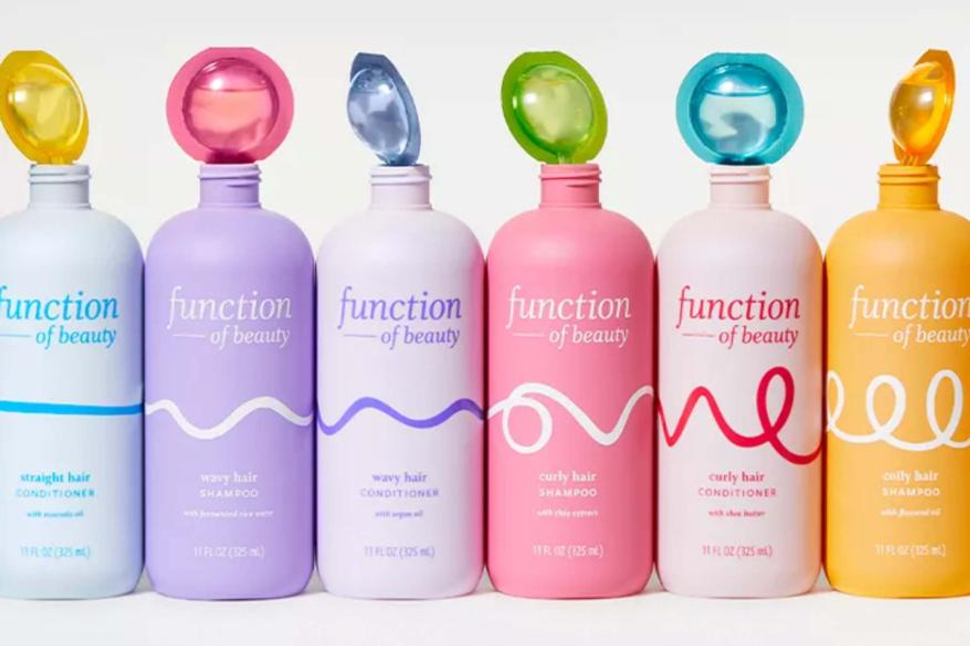 Five bottles of Function of Beauty's personalized hair care products lined up in a row, representing the brand's commitment to customization and eco-friendly practices in the hair care industry