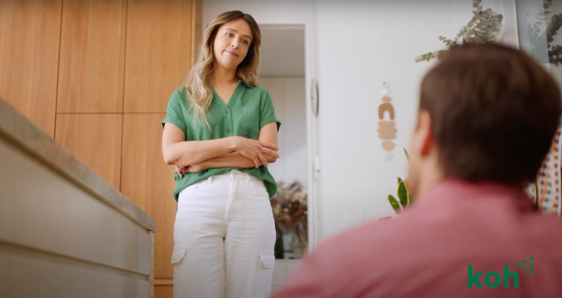 A woman in a green shirt and a man in a pink shirt, representing a humorous dynamic in household chores as part of Koh's brand awareness campaign