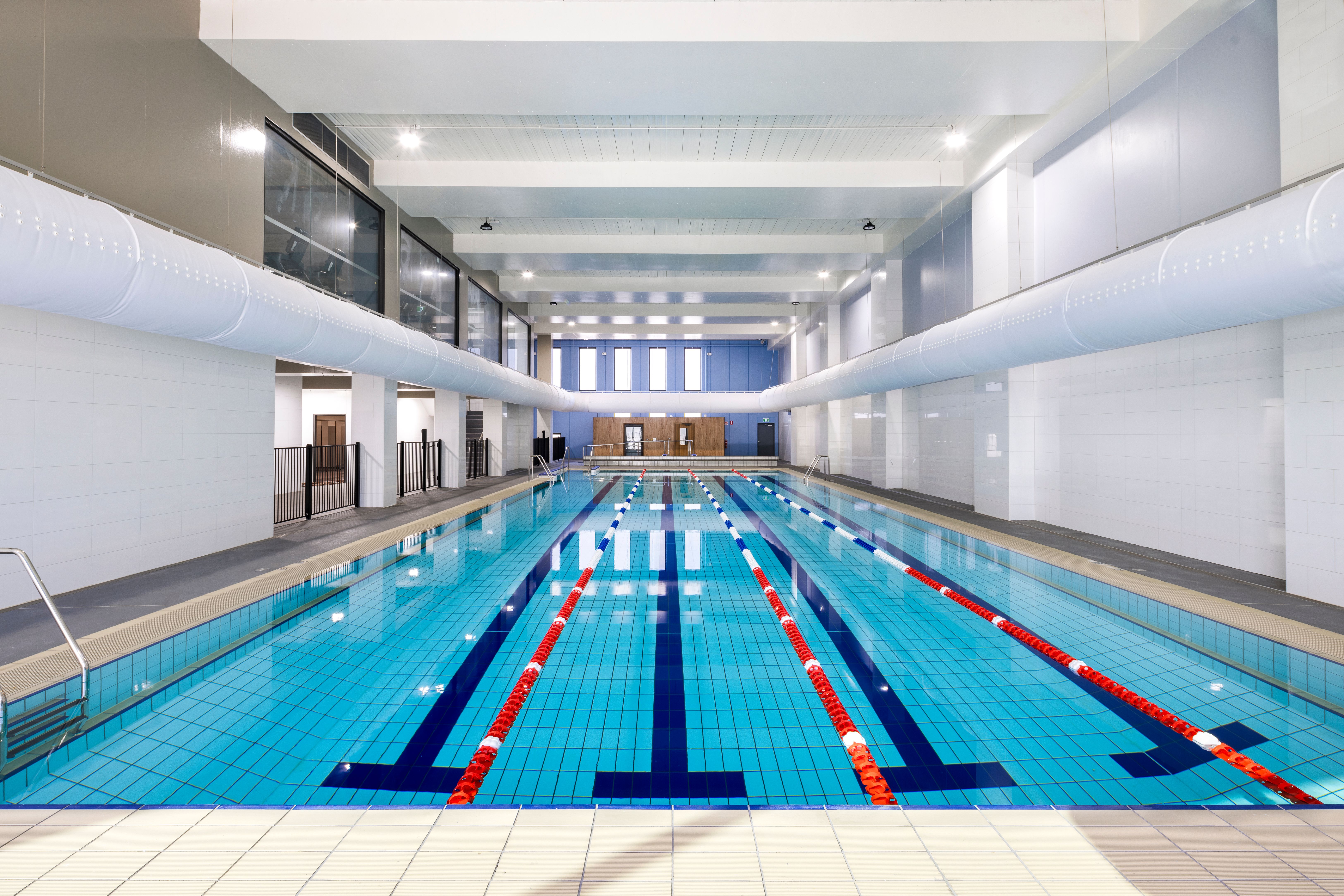 An empty, modern indoor swimming pool with multiple lanes.