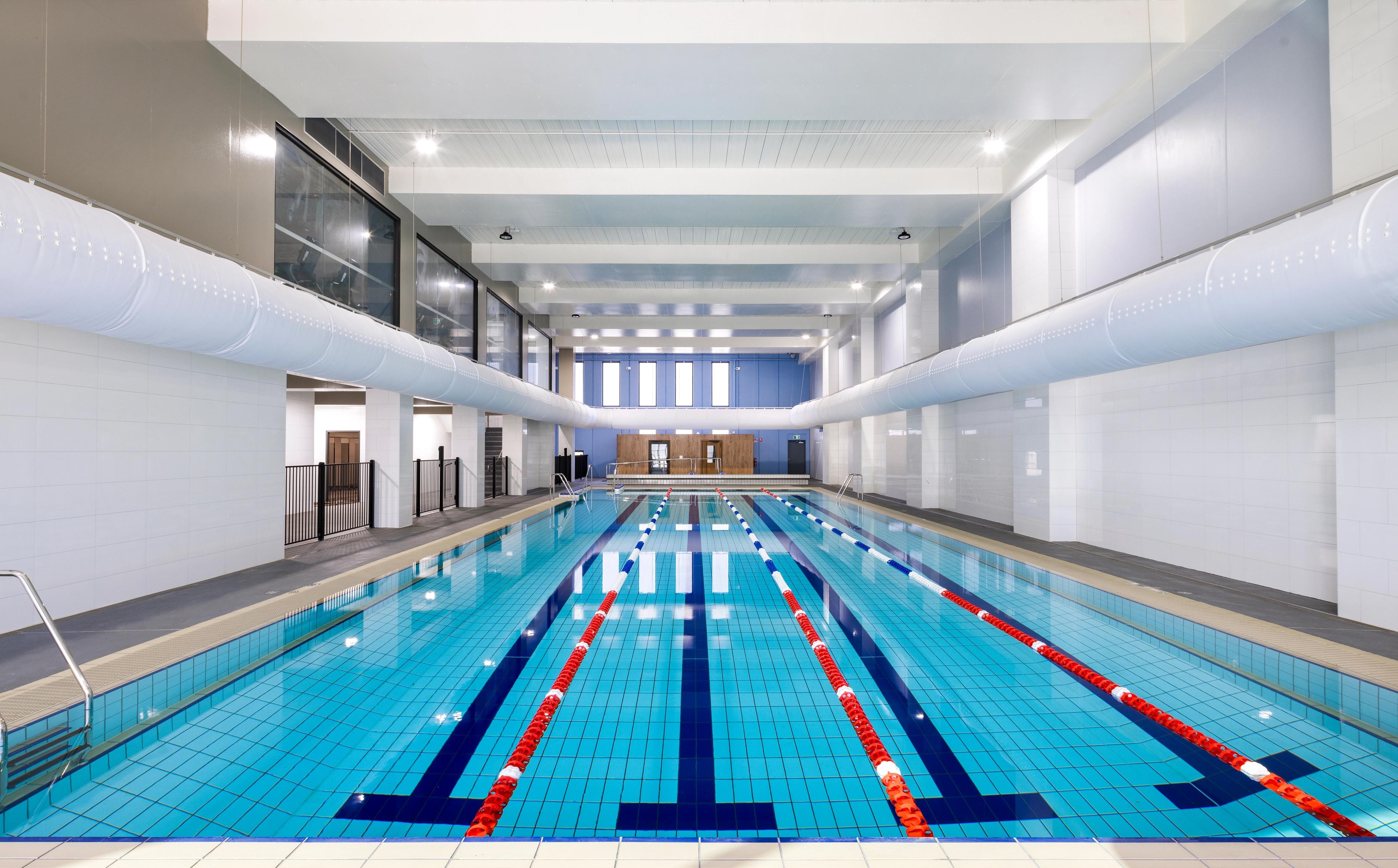 An empty, modern indoor swimming pool with multiple lanes.