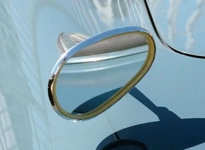 Close-up of a side mirror on a baby blue car