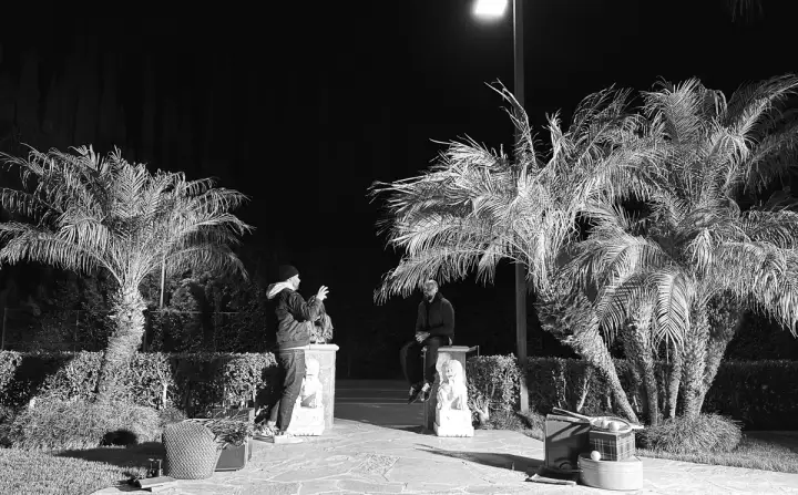 Two creatives talk under the palm trees on set