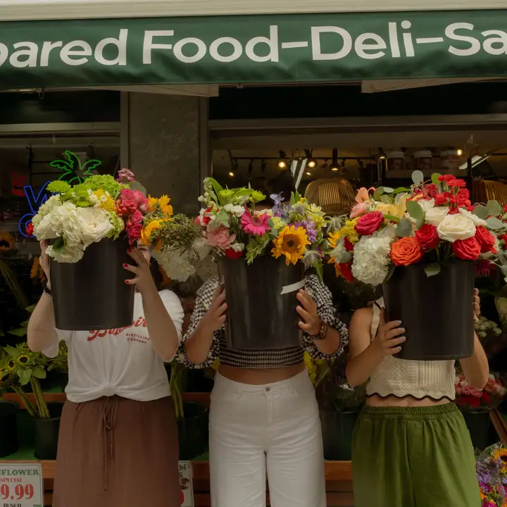 Three people holding up buckets of flowers