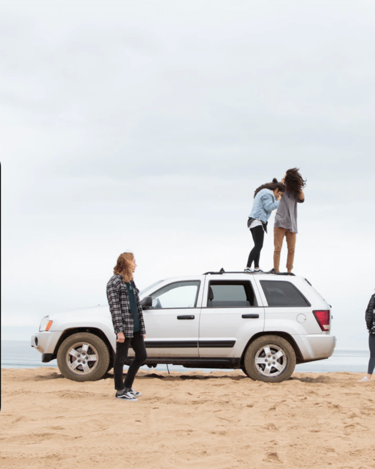 Familj och vänner runt en parkerad vit jeep på en sandstrand med havet i bakgrunden, intill en mobilskärm med en gruppdröm "Roadtrip" och saldot 16 000 kr.