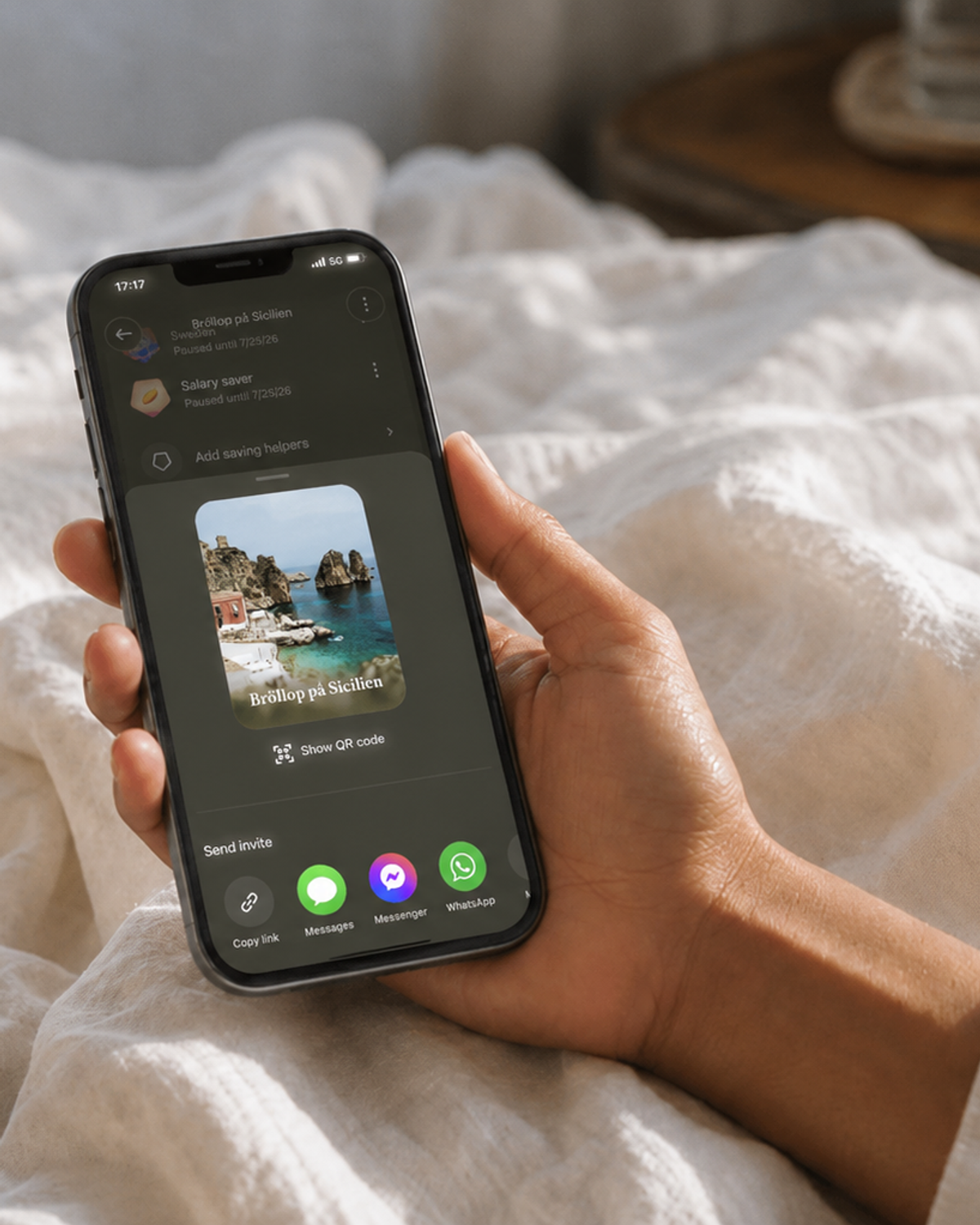 En person håller en mobiltelefon med en inbjudan till en delad Dreams-dröm för ett bröllop på Sicilien.