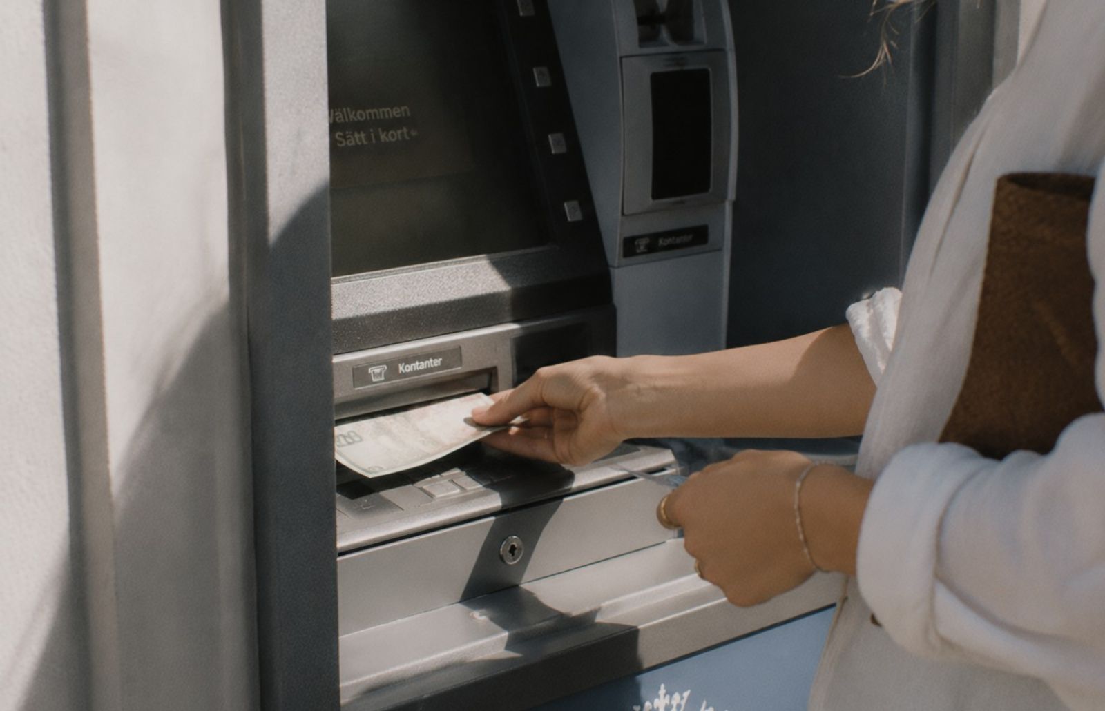 En person som tar ut kontanter ur en bankomat.