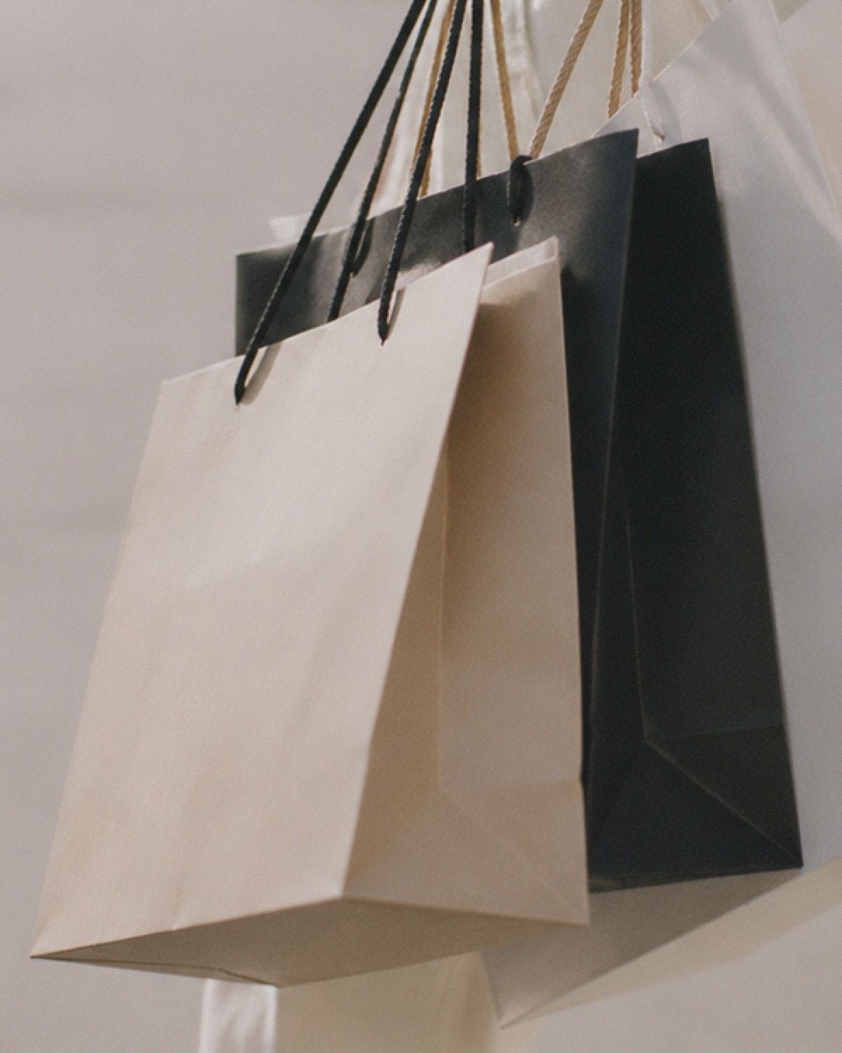 Tre shoppingpåsar i beige, svart och vitt