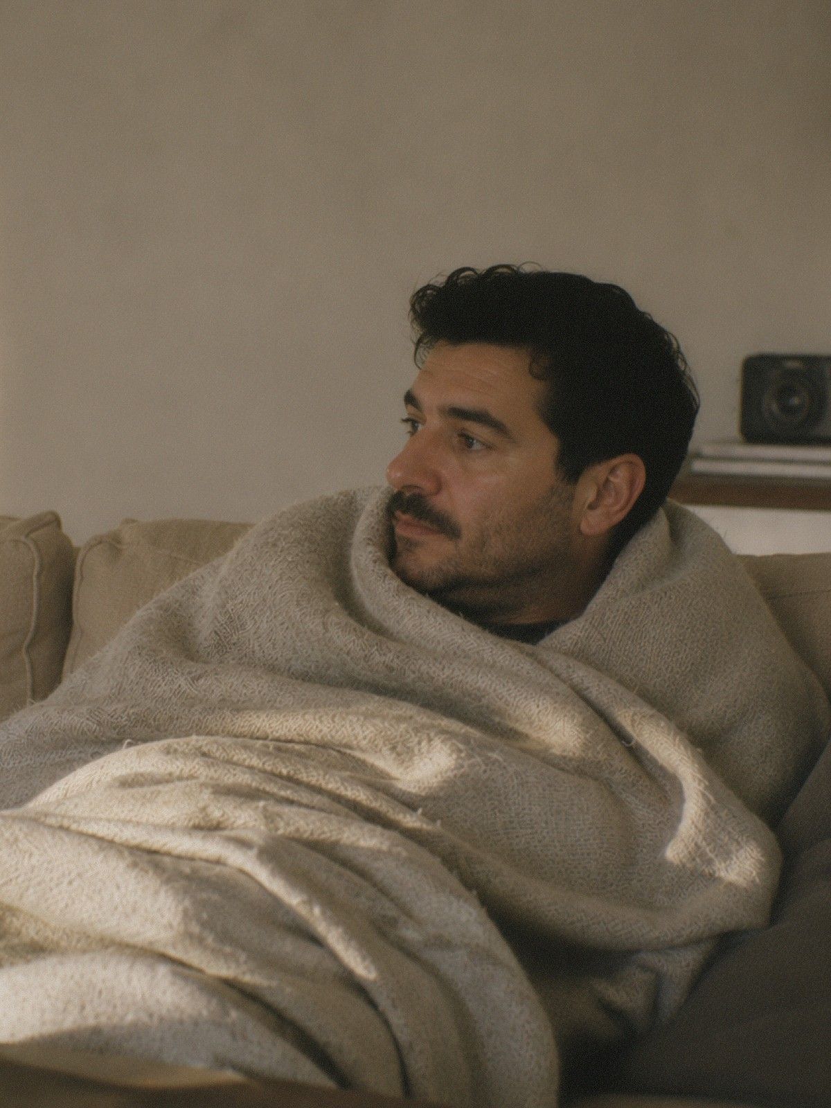 En man invirad i en filt i en soffa.