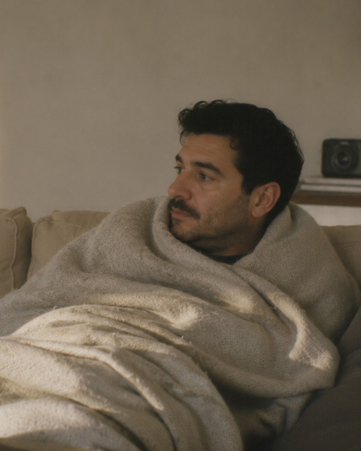 En man invirad i en filt i en soffa.