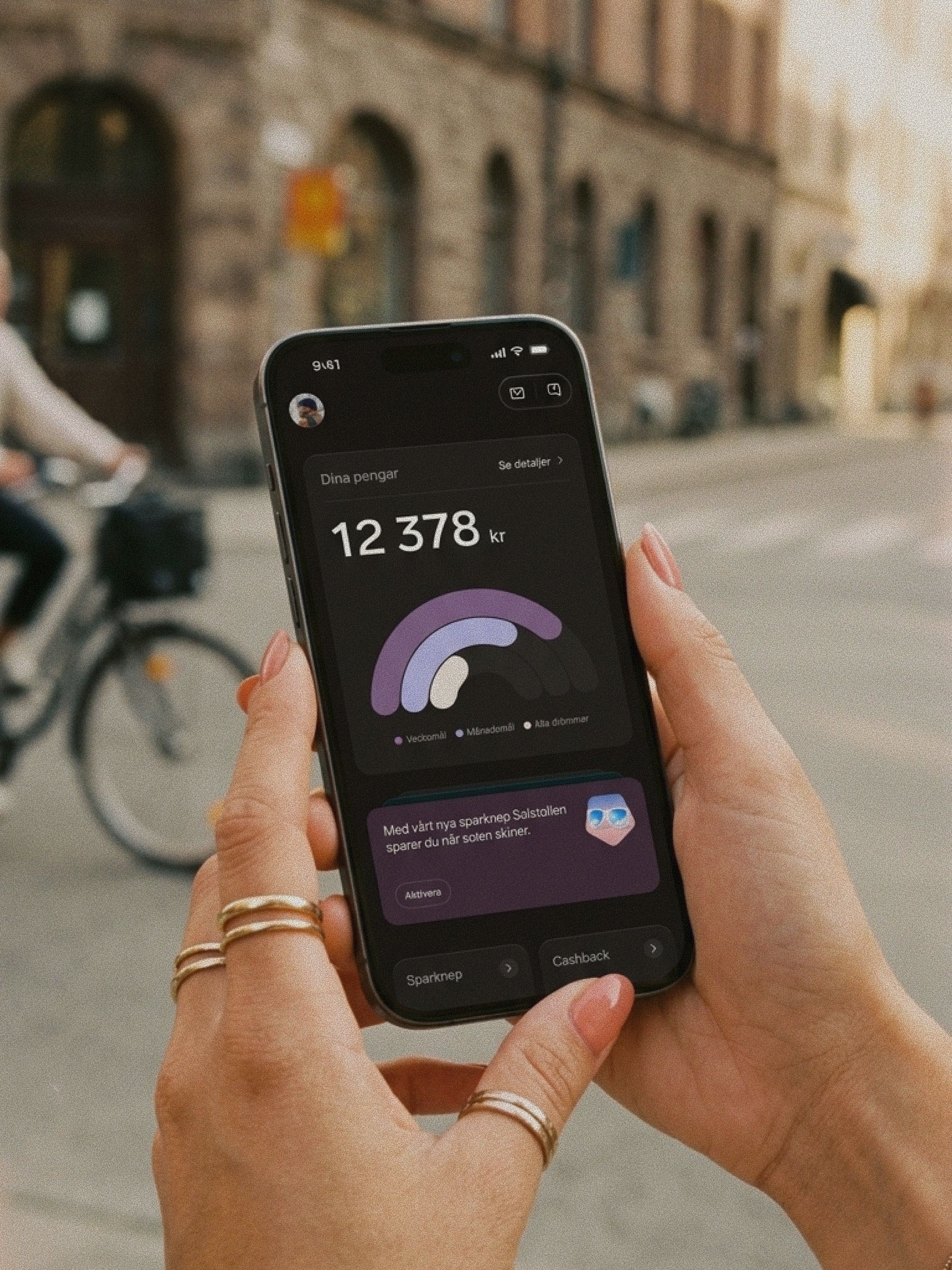 En person med ringar och persikofärgat nagellack håller en mobiltelefon som visar en sparöversikt i Dreams.