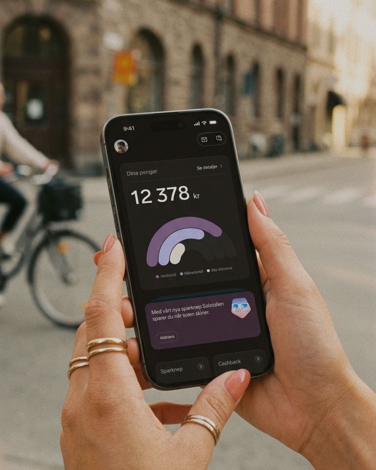 En person med ringar och persikofärgat nagellack håller en mobiltelefon som visar en sparöversikt i Dreams.