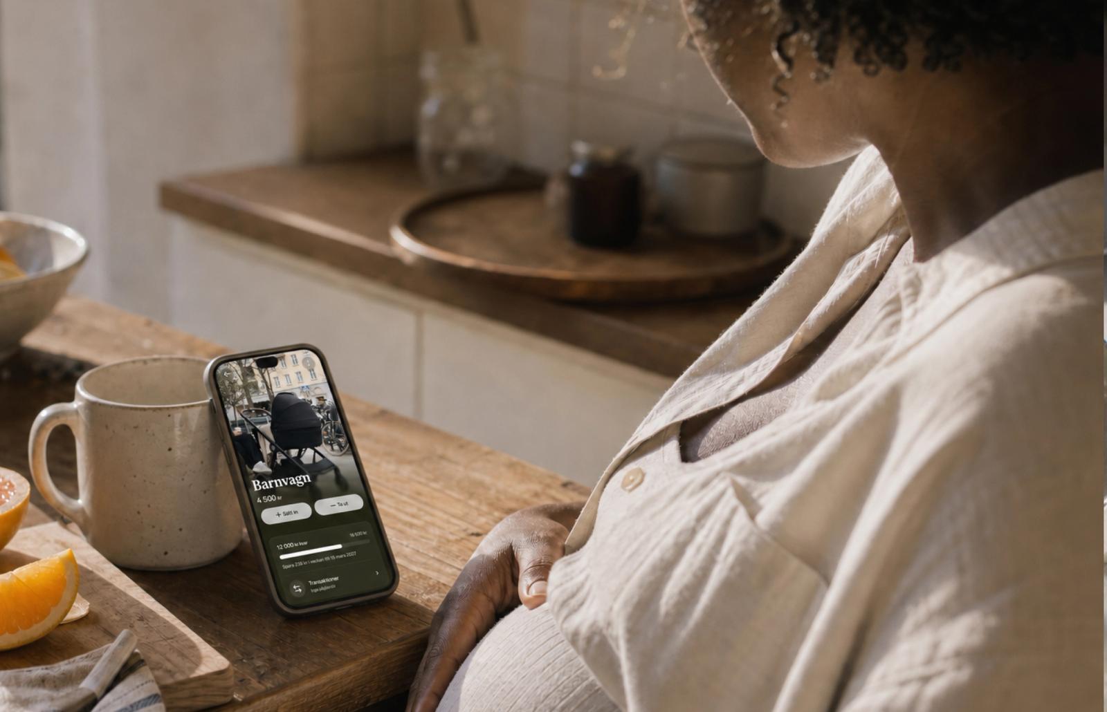 En gravid person tittar på en mobiltelefon som visar en Dreams-dröm för en barnvagn.