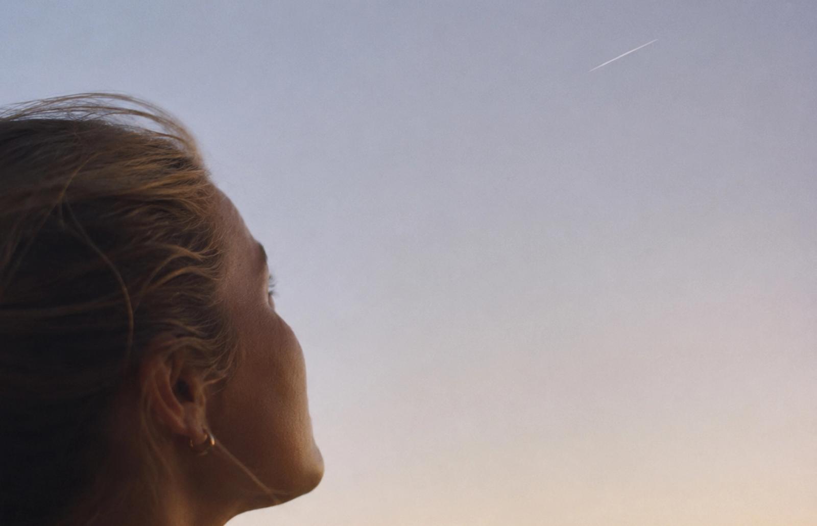En person tittar upp mot en satellit som rör sig över himlen.