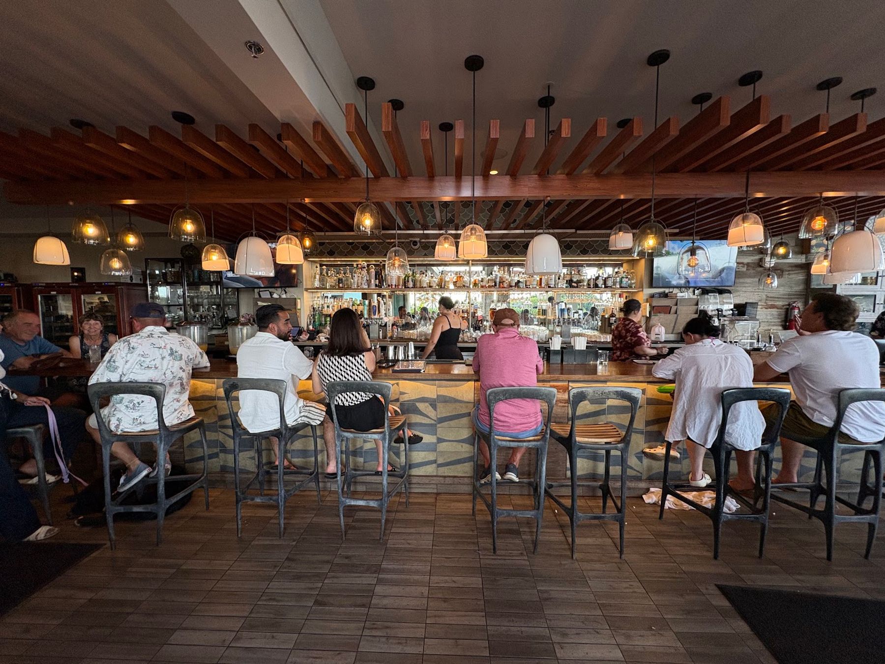 Guests seated at the bar inside the open-air dining room at DECK.