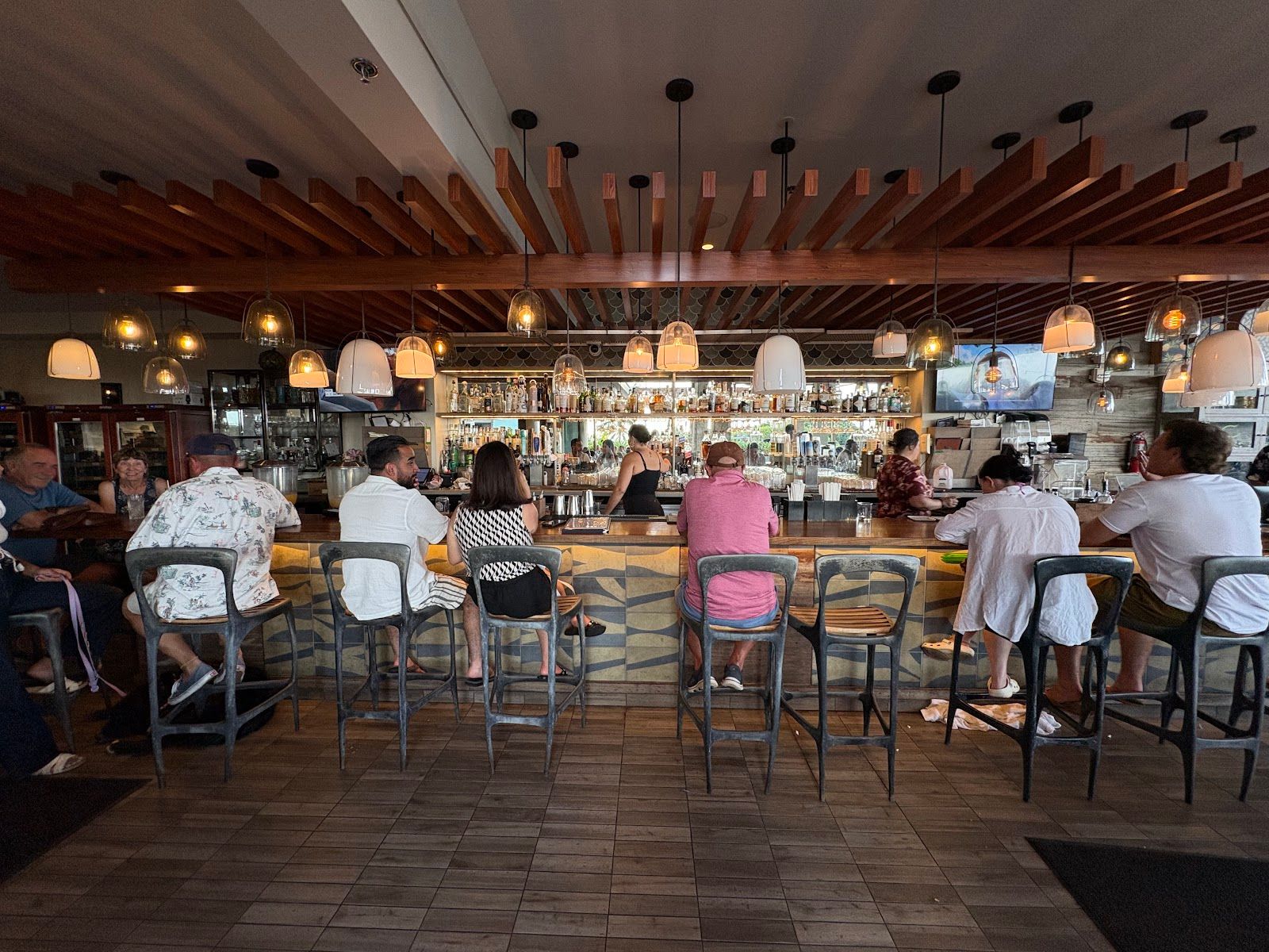 Guests seated at the bar inside the open-air dining room at DECK.