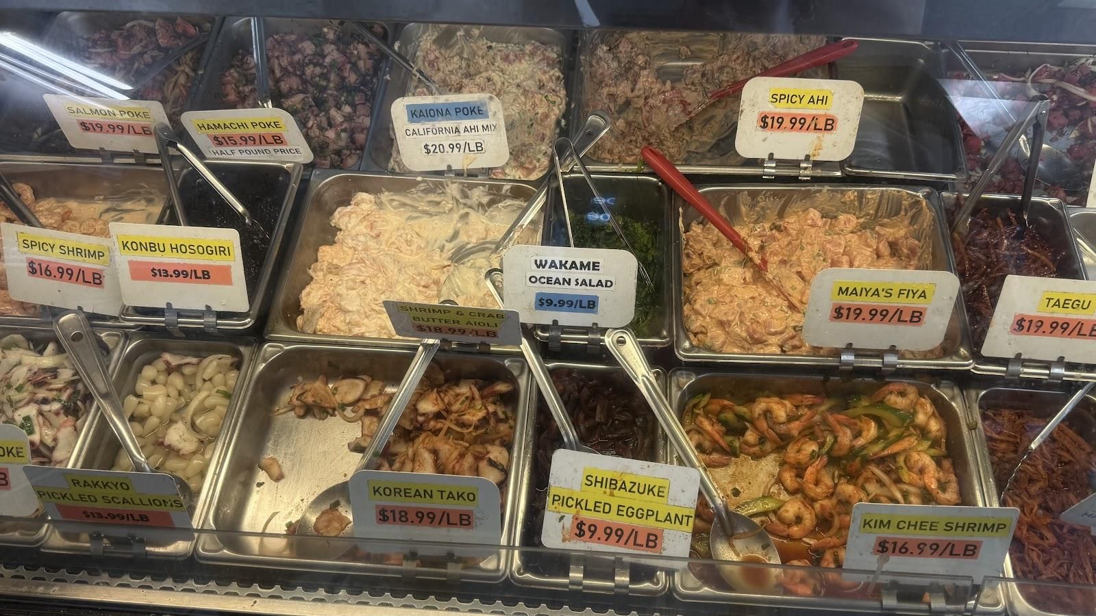 Colorful poke counter display featuring fresh ahi, salmon, and various Hawaiian-style preparations