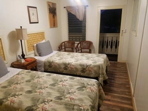 Cozy budget hotel room at Kauai Palms with tropical print bedspreads and balcony access