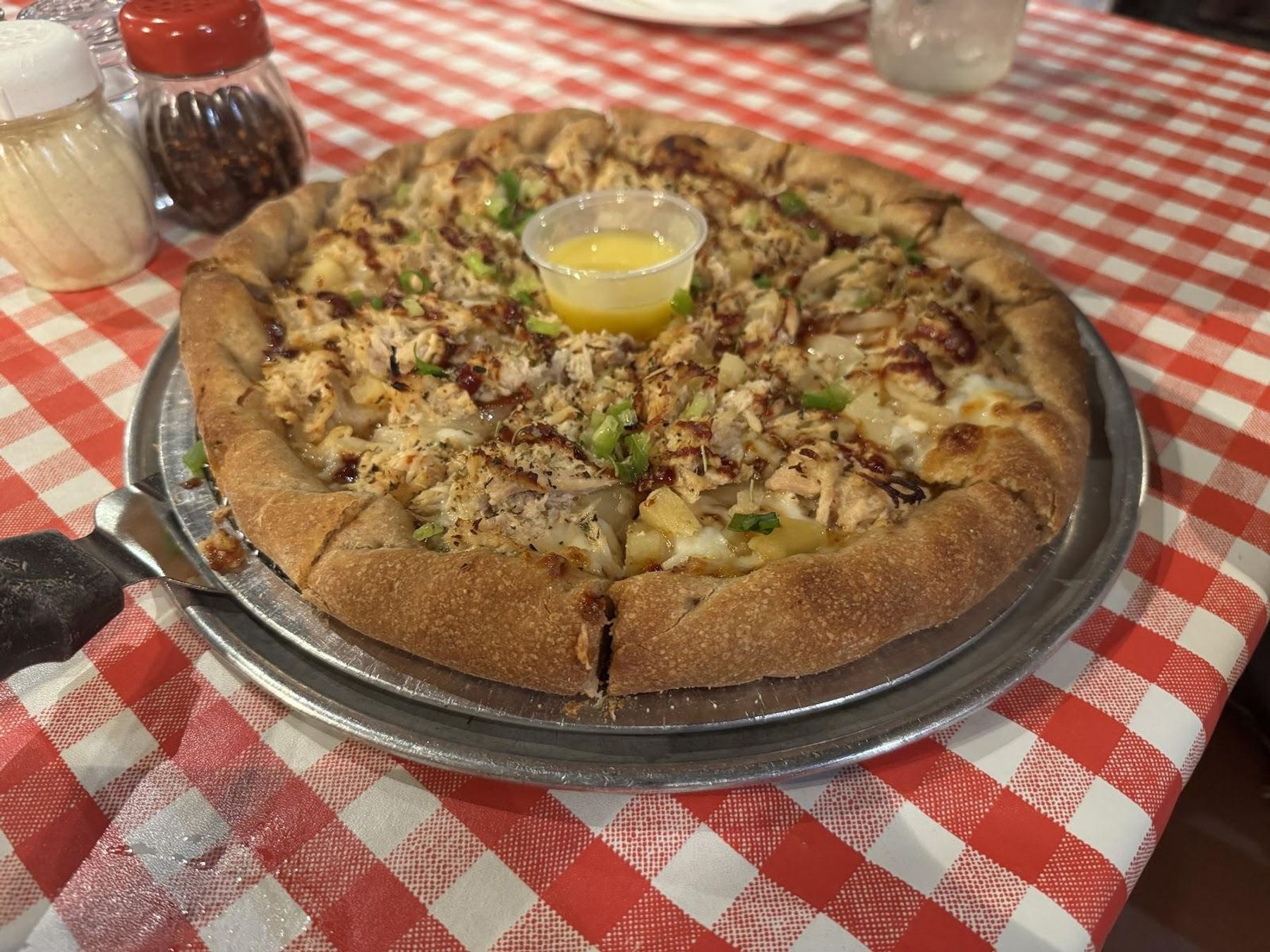 Golden brick oven pizza with melted cheese on classic red checkered tablecloth
