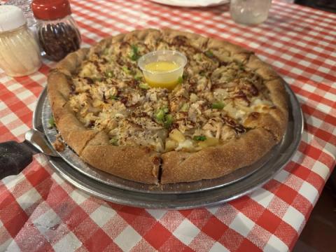 Golden brick oven pizza with melted cheese on classic red checkered tablecloth