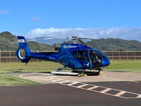 Blue Hawaiian helicopter on helipad ready for a scenic tour over Kauai with mountains in the background
