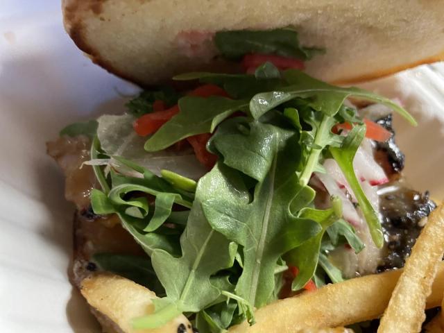 Gourmet burger topped with fresh arugula and melted cheese served with crispy fries