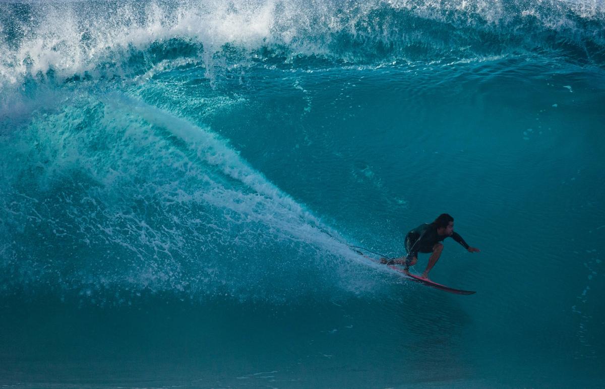 Surfer riding inside a curling ocean wave on Oʻahu’s North Shore.