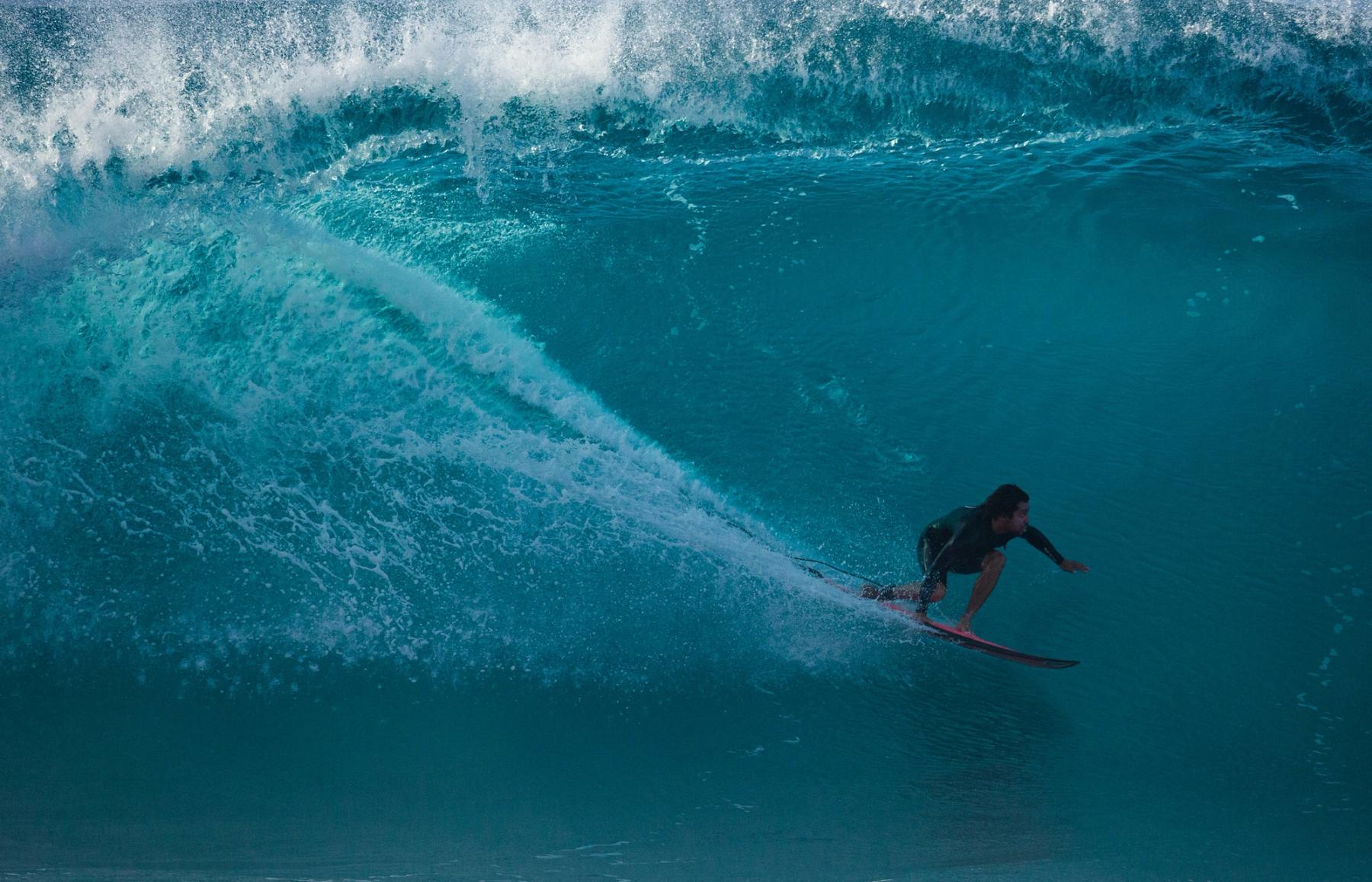 Surfer riding inside a curling ocean wave on Oʻahu’s North Shore.