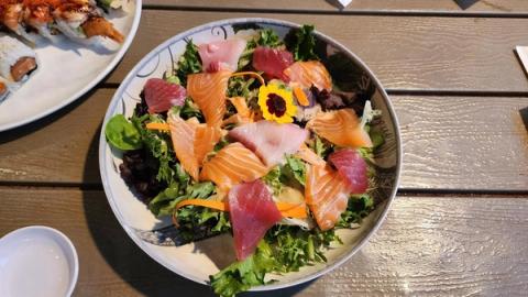 Vibrant sashimi salad bowl with fresh salmon, tuna, and edible flowers from a Kauai food truck