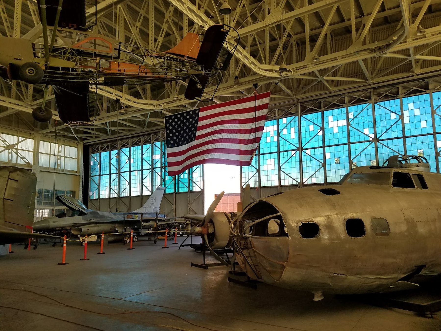 Aircraft exhibits and an American flag inside one of Pearl Harbor Aviation Museum's Ford Island hangars.