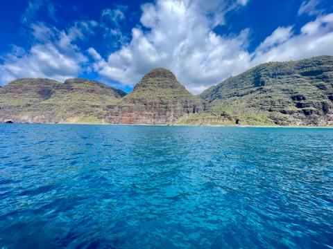 Crystal clear turquoise waters along the Na Pali Coast perfect for snorkeling with dramatic cliffs rising above