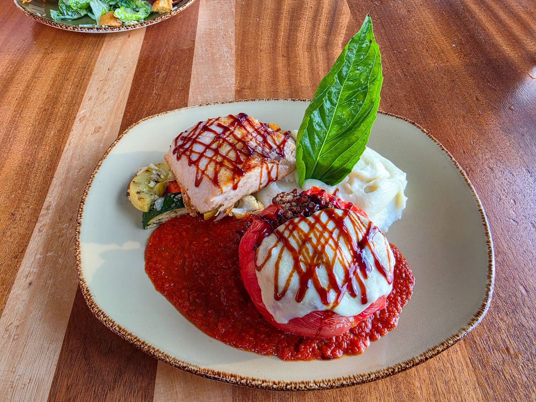 A colorful plated entree at Huggo's with red sauce and fresh basil.
