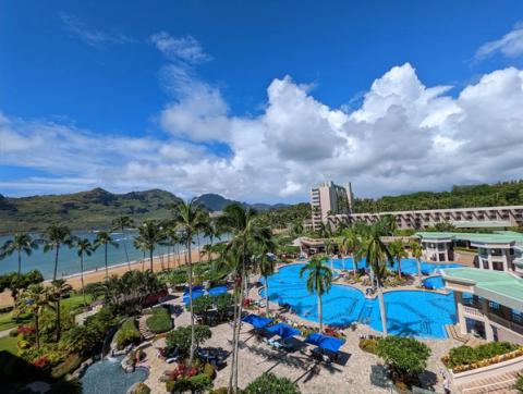 Aerial view of Royal Sonesta resort pools, beach, and lush mountains at Kalapaki Bay