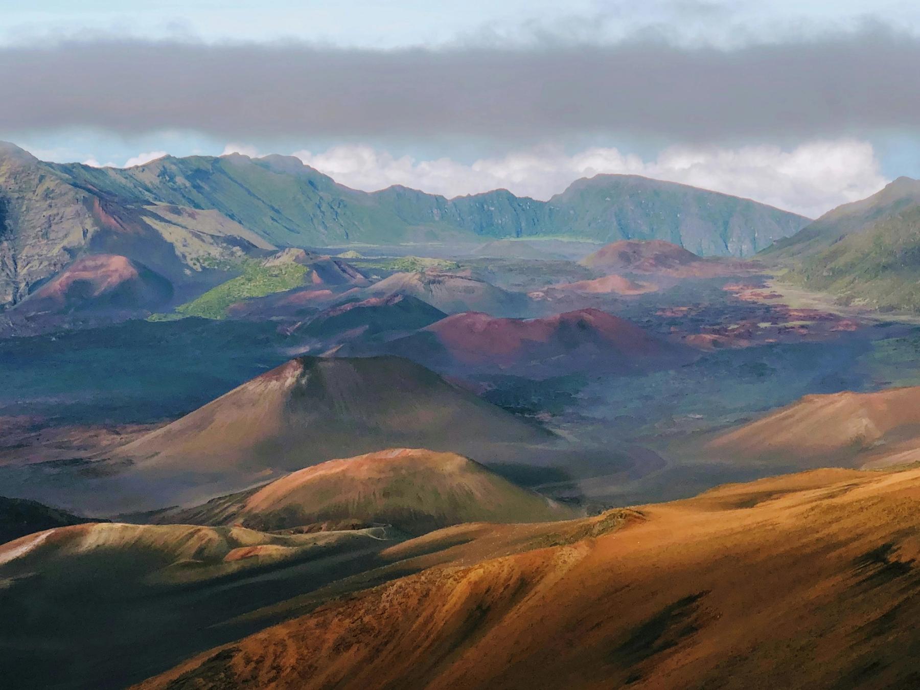 Volcanic cinder cones and rugged crater walls under low clouds in Haleakalā Crater near Kula, Maui.