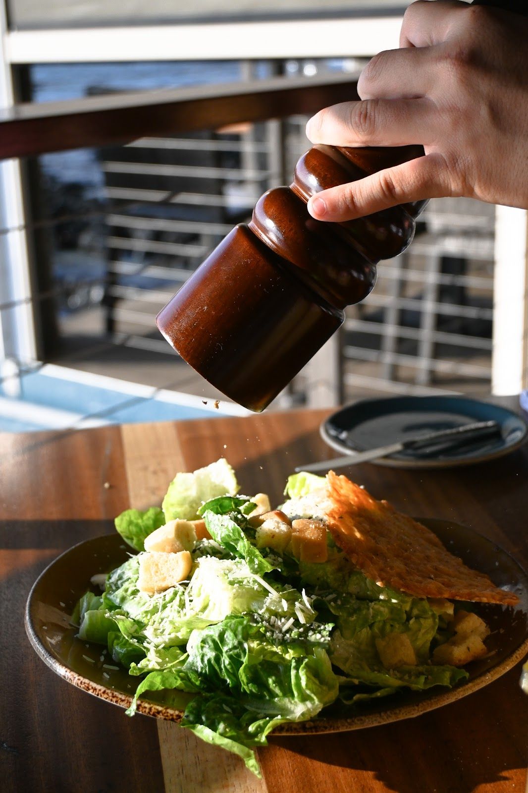 A plated seafood dish being seasoned at Huggo's beside the waterfront.
