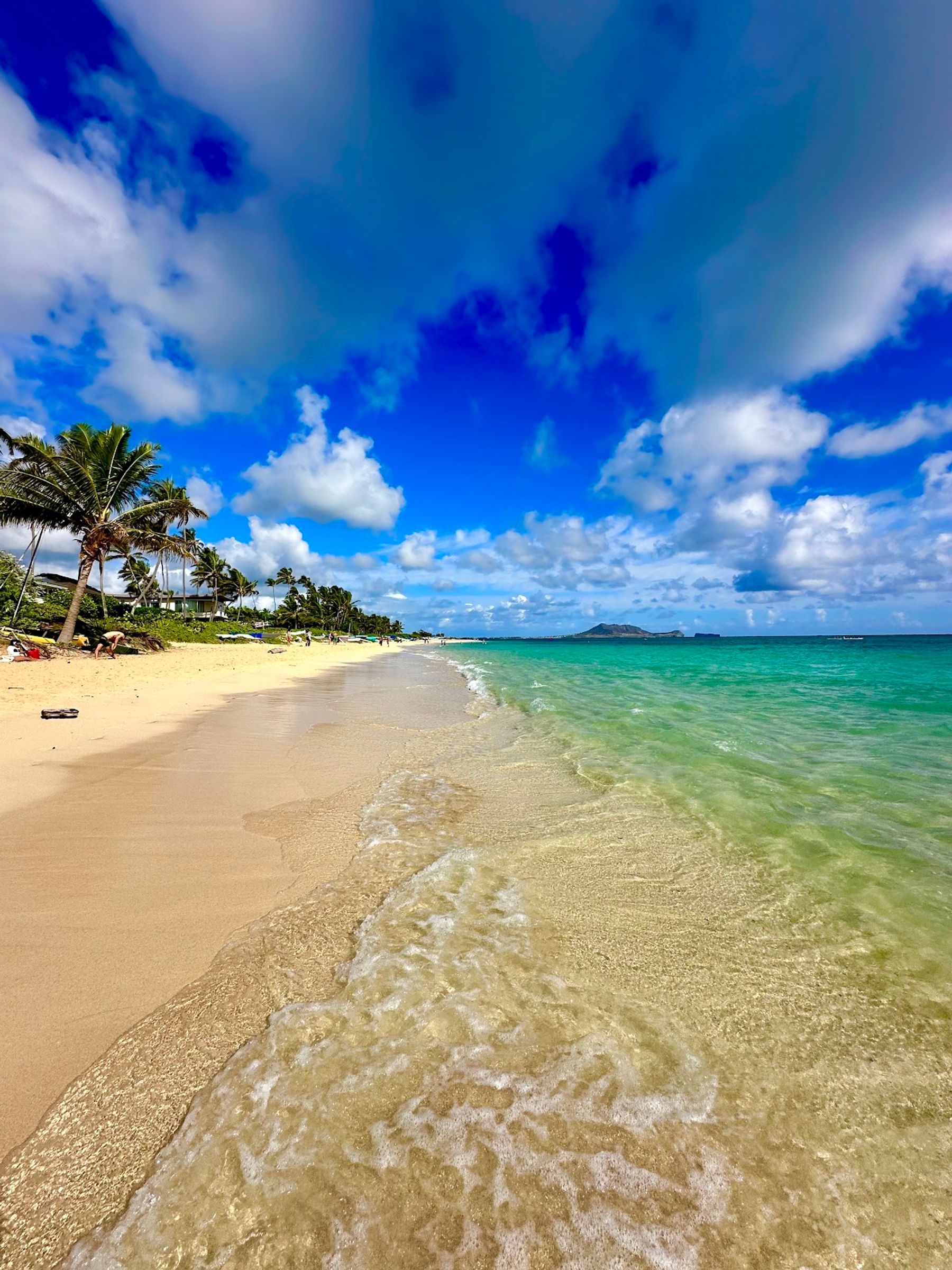 Clear shallow water washing onto the sand along the Lanikai Beach shoreline.