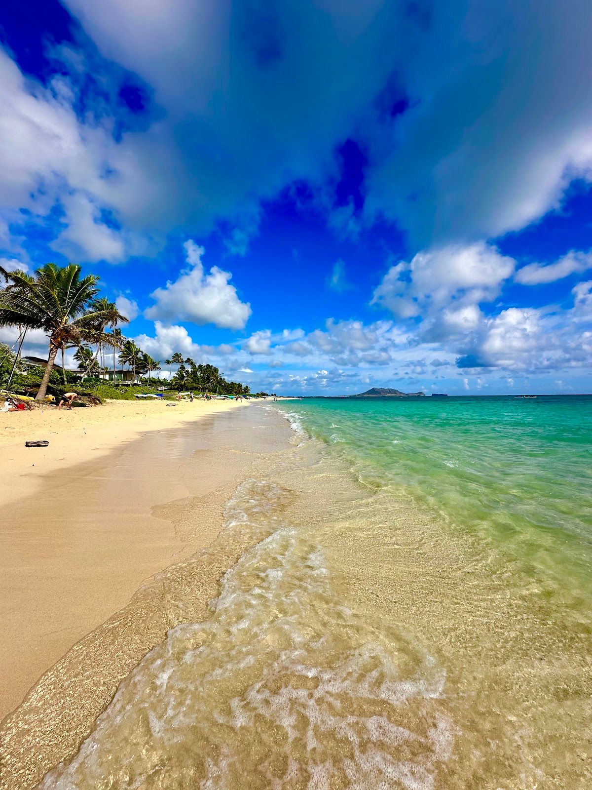 Clear shallow water washing onto the sand along the Lanikai Beach shoreline.