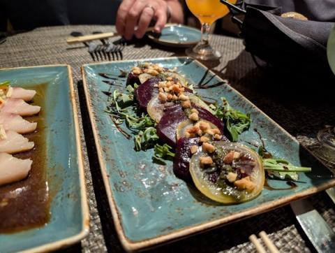 Elegant fine dining presentation of sashimi and roasted beet salad with tropical cocktail at Tidepools