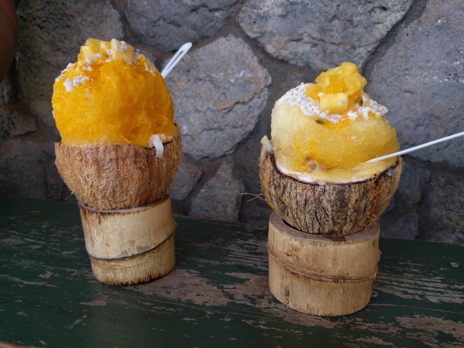 Tropical shave ice served in coconut shells topped with fresh mango and lilikoi