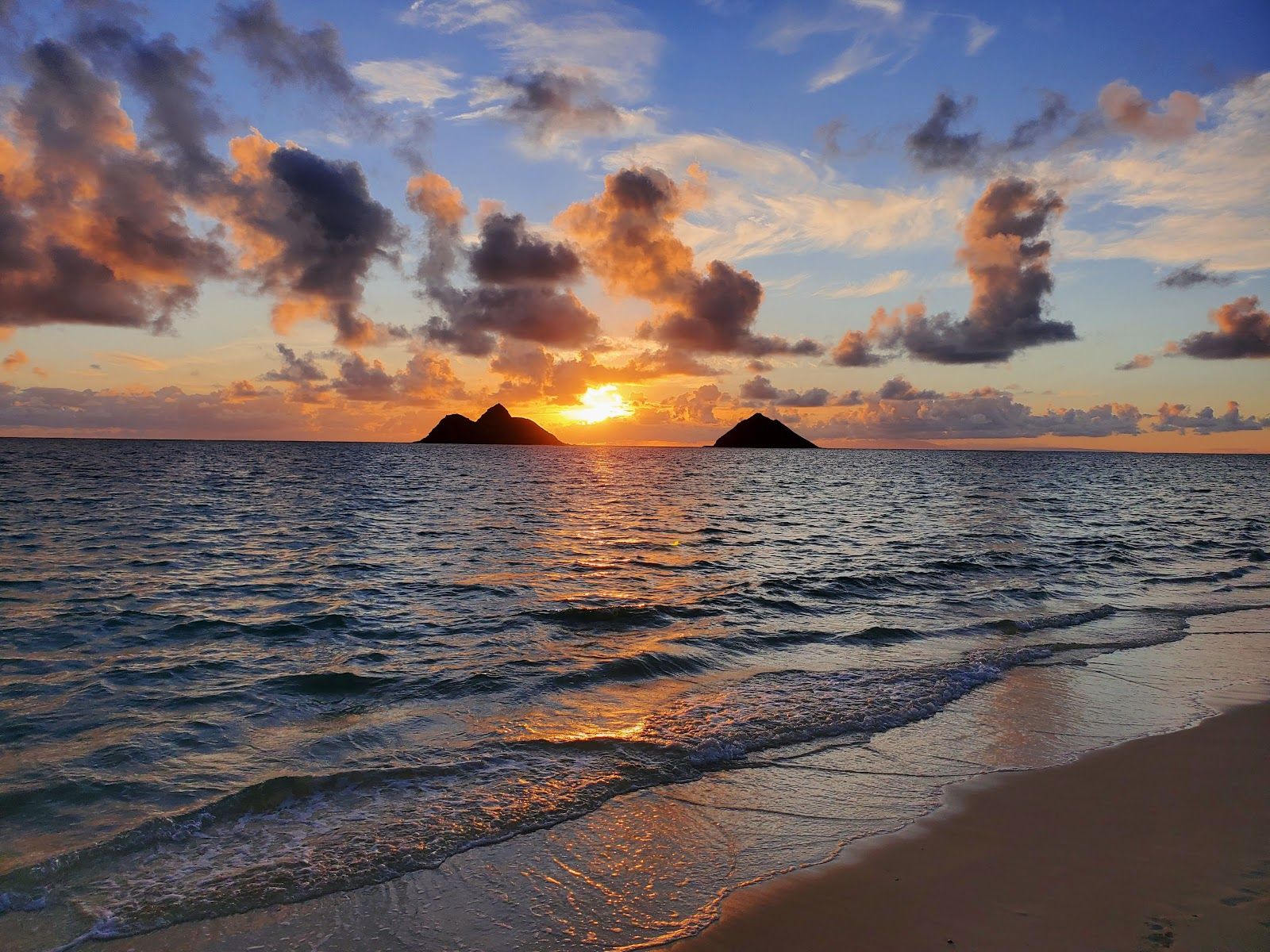 Sunrise over the Mokulua Islands from the waterline at Lanikai Beach.